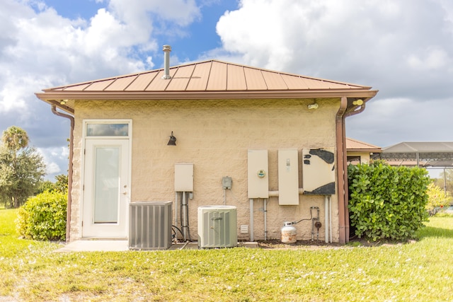 back of house with central air condition unit and a yard