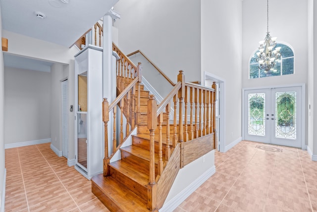 tiled entryway featuring french doors, a towering ceiling, and a notable chandelier