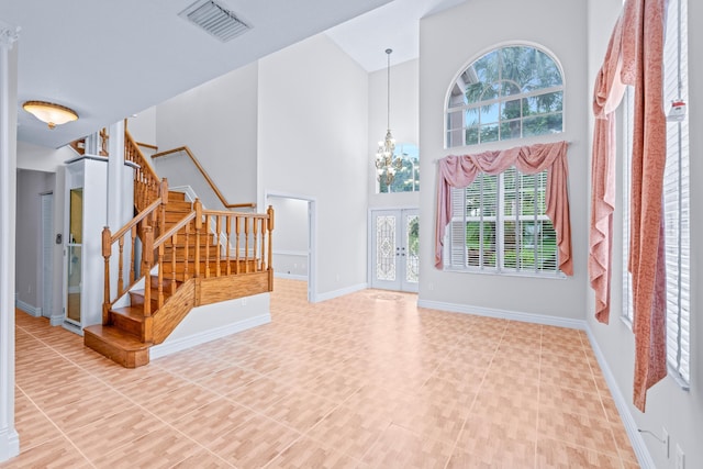 foyer entrance featuring french doors, a high ceiling, and a notable chandelier