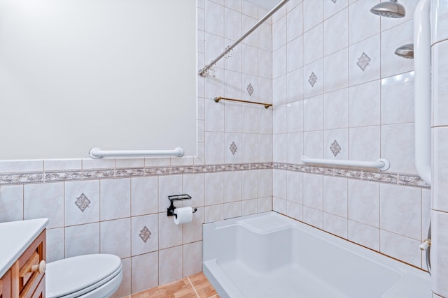 bathroom with a tile shower, vanity, tile walls, tile patterned flooring, and toilet