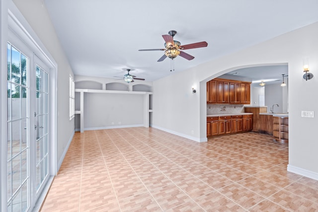 unfurnished living room featuring ceiling fan, sink, and light tile patterned floors