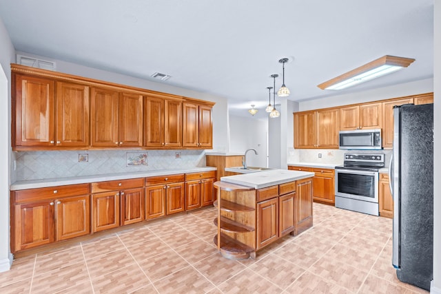 kitchen featuring a kitchen island with sink, hanging light fixtures, sink, decorative backsplash, and appliances with stainless steel finishes