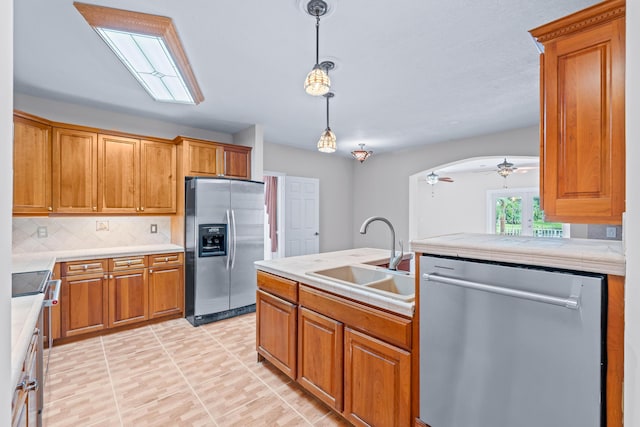 kitchen featuring backsplash, stainless steel appliances, ceiling fan, sink, and pendant lighting