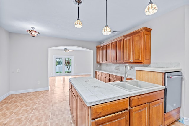 kitchen with decorative light fixtures, ceiling fan, sink, and tasteful backsplash