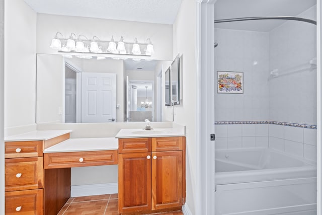 bathroom with a textured ceiling, vanity, tiled shower / bath, and tile patterned flooring