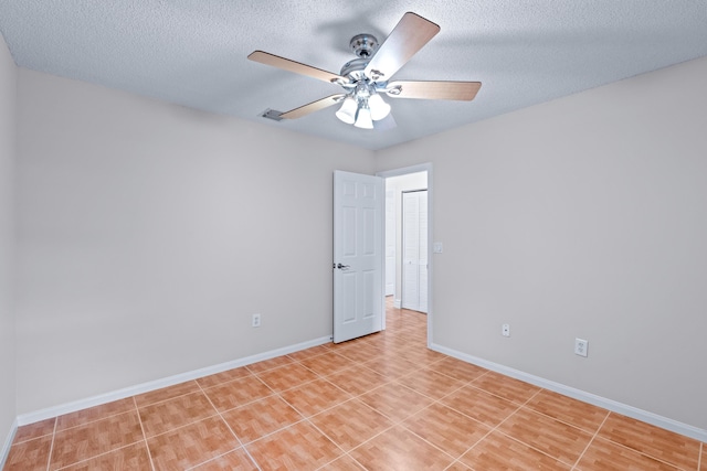 tiled spare room featuring a textured ceiling and ceiling fan