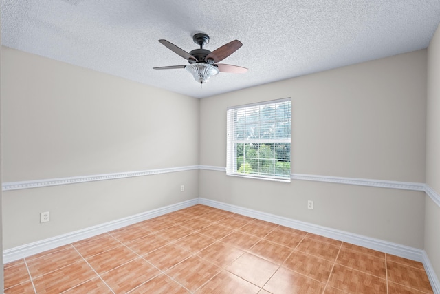 tiled spare room with a textured ceiling and ceiling fan