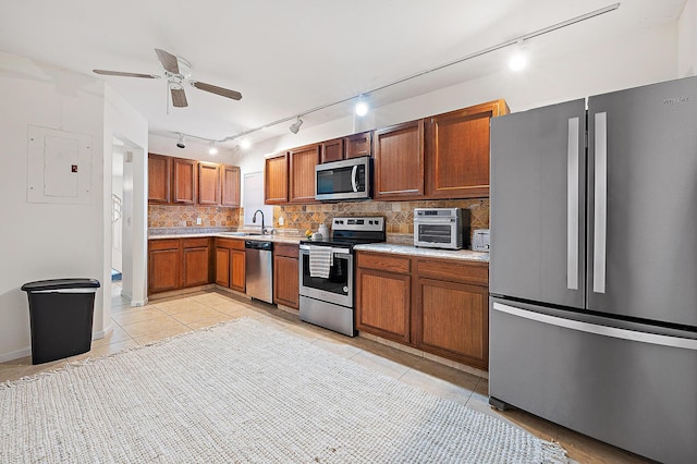 kitchen featuring appliances with stainless steel finishes, light countertops, light tile patterned floors, tasteful backsplash, and rail lighting