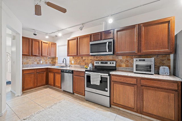 kitchen with appliances with stainless steel finishes, a sink, light countertops, light tile patterned flooring, and a ceiling fan
