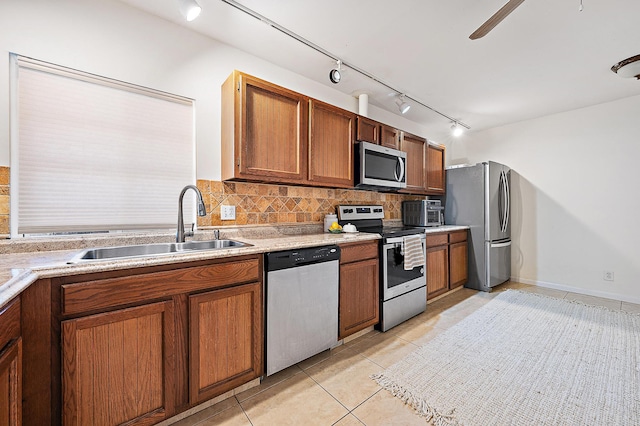 kitchen with light tile patterned flooring, sink, track lighting, appliances with stainless steel finishes, and decorative backsplash