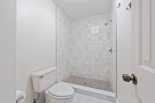 bathroom with a tile shower, tile patterned floors, and toilet