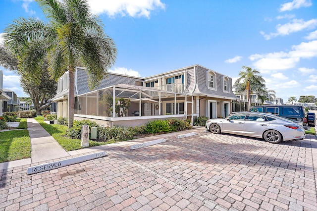 view of front of property with a balcony and glass enclosure