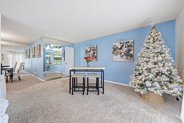 dining area featuring carpet, baseboards, and a textured ceiling