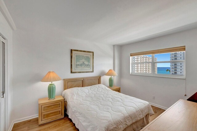 bedroom with a water view and light hardwood / wood-style flooring