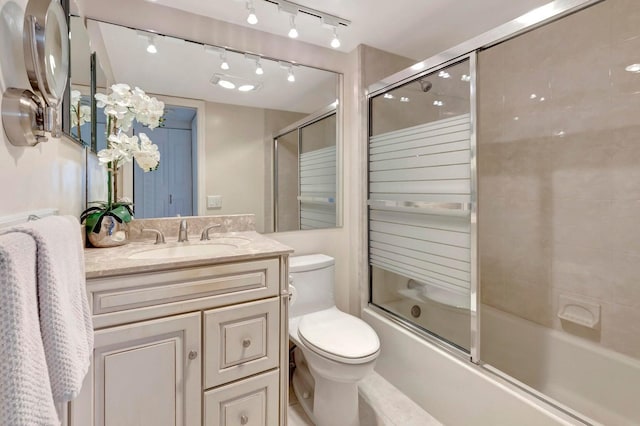 full bathroom featuring combined bath / shower with glass door, vanity, and toilet