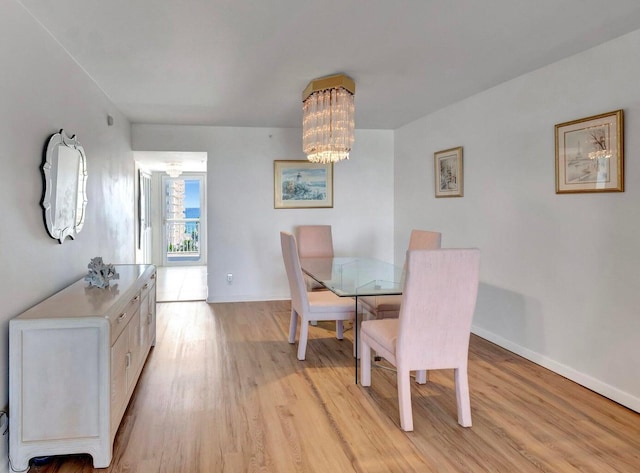 dining space with light hardwood / wood-style flooring and a notable chandelier