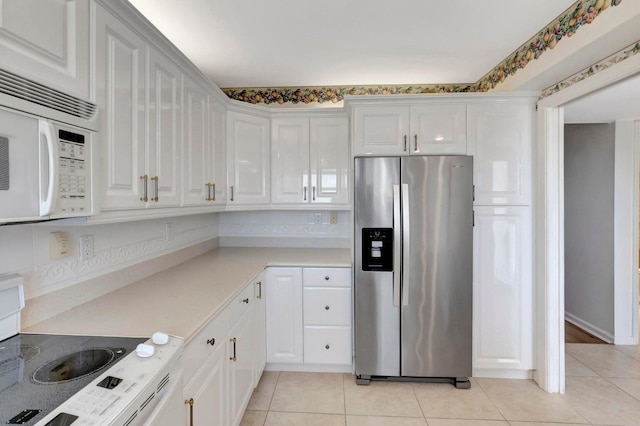 kitchen featuring white appliances, white cabinetry, and light tile patterned flooring