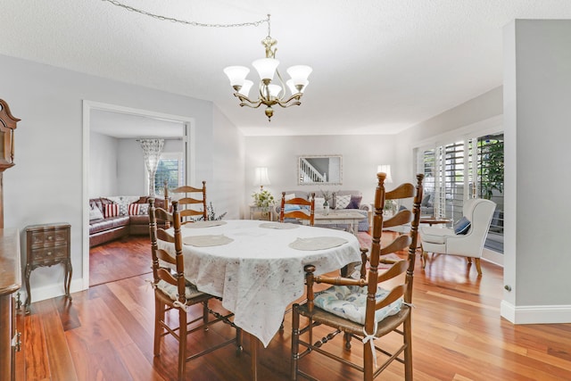 dining area with wood-type flooring, plenty of natural light, and a notable chandelier