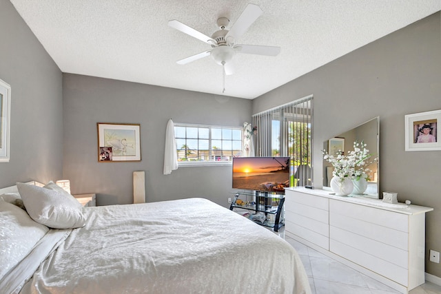 bedroom featuring light tile patterned flooring, ceiling fan, and a textured ceiling