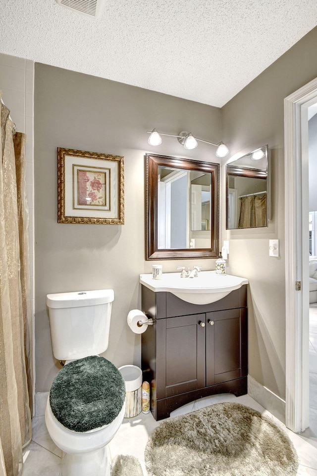 bathroom with tile patterned flooring, vanity, a textured ceiling, and toilet