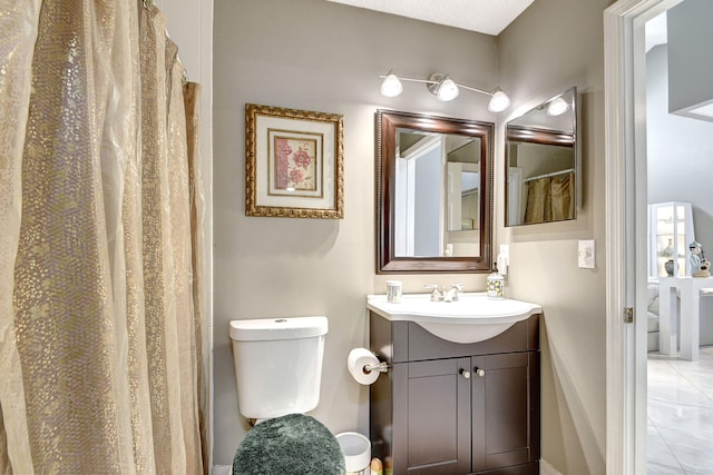 bathroom with toilet, vanity, and tile patterned floors