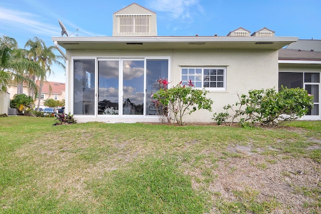 back of property with a sunroom, a yard, and central AC