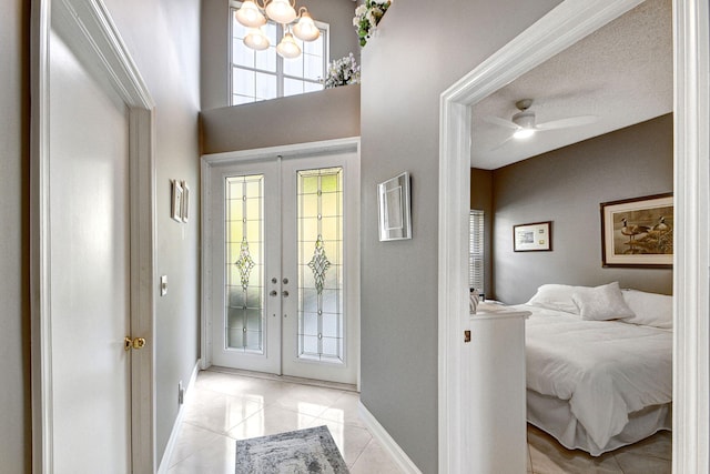 entryway featuring ceiling fan, a wealth of natural light, french doors, and light tile patterned flooring