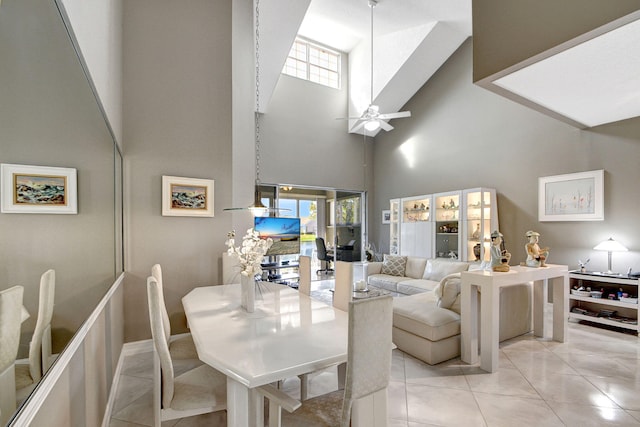 dining space featuring a towering ceiling, ceiling fan, and light tile patterned floors