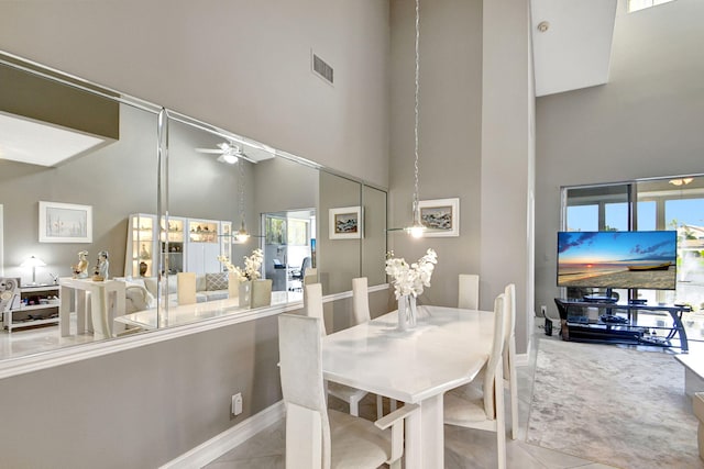 dining area with a towering ceiling, ceiling fan, and tile patterned flooring