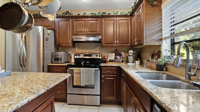 kitchen with light stone counters, sink, light tile patterned flooring, and stainless steel appliances