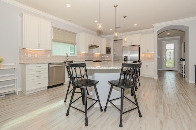 kitchen with a center island, white cabinets, stainless steel appliances, and decorative light fixtures