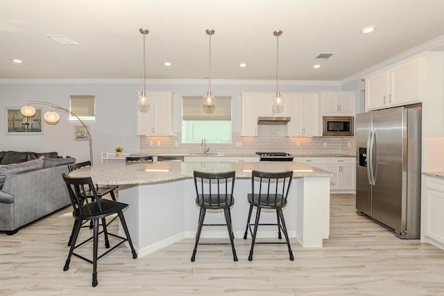 kitchen with a center island, sink, hanging light fixtures, stainless steel appliances, and white cabinets