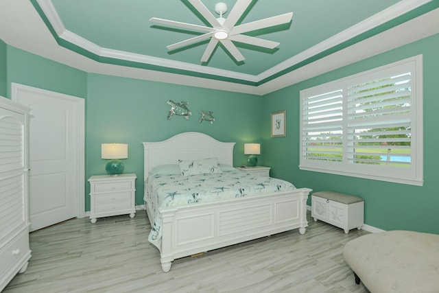 bedroom featuring a tray ceiling, ceiling fan, light hardwood / wood-style flooring, and ornamental molding