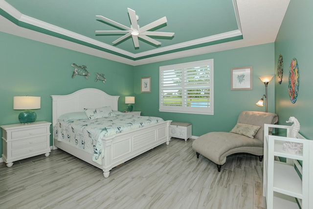 bedroom with a raised ceiling, ceiling fan, light hardwood / wood-style floors, and ornamental molding