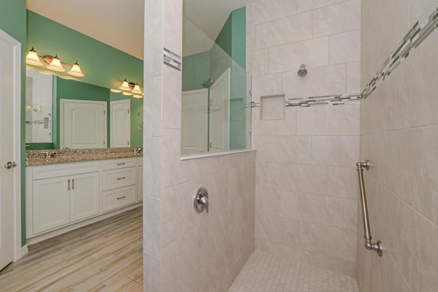 bathroom with a tile shower, vanity, and vaulted ceiling