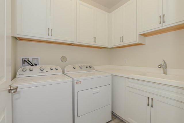 clothes washing area with washer and clothes dryer, cabinets, and sink