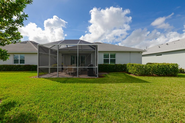 back of property featuring a lawn, glass enclosure, and a patio area