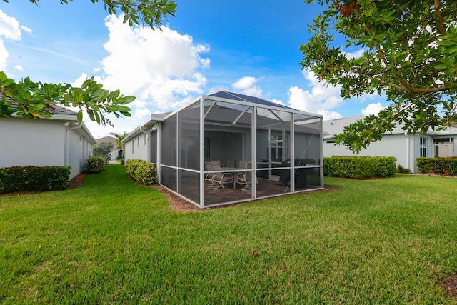 back of property featuring a lawn and glass enclosure