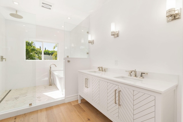 bathroom featuring vanity, wood-type flooring, and plus walk in shower