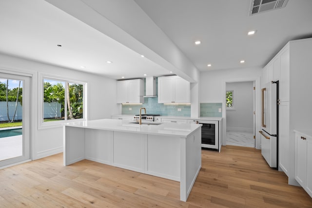 kitchen with wine cooler, high end fridge, light wood-type flooring, and white cabinets