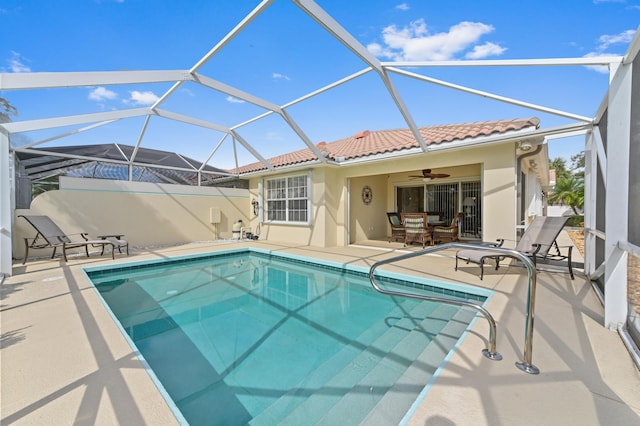 view of swimming pool with glass enclosure, ceiling fan, and a patio