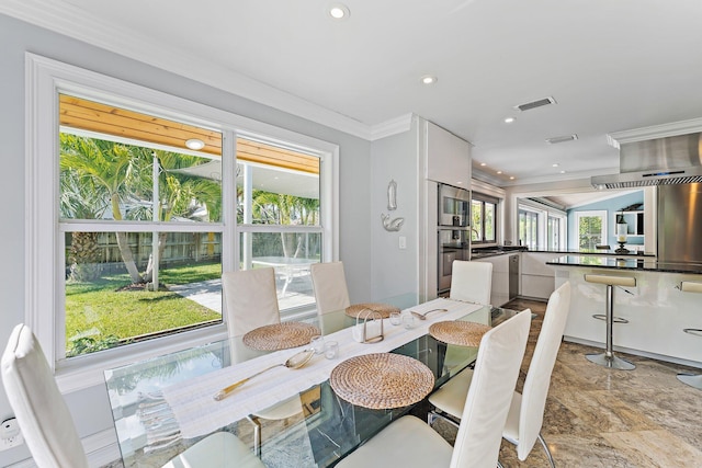 dining space featuring ornamental molding and plenty of natural light