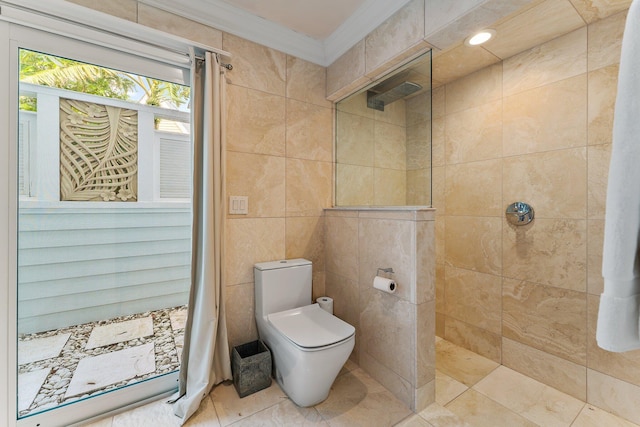 bathroom featuring a tile shower, ornamental molding, toilet, and tile walls