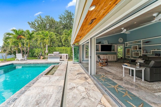 view of pool featuring a patio, a grill, an outdoor kitchen, and ceiling fan