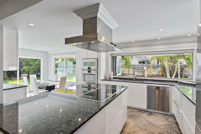 kitchen featuring white cabinets, wall chimney range hood, plenty of natural light, and dishwasher