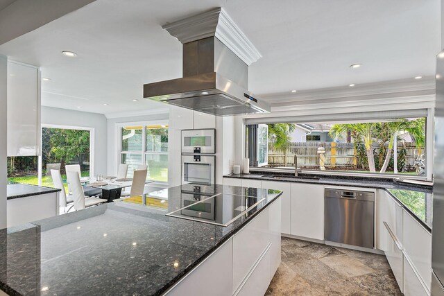 kitchen featuring white cabinetry, stainless steel appliances, a breakfast bar area, and range hood