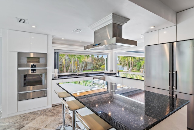 kitchen with white cabinetry, island exhaust hood, appliances with stainless steel finishes, and sink