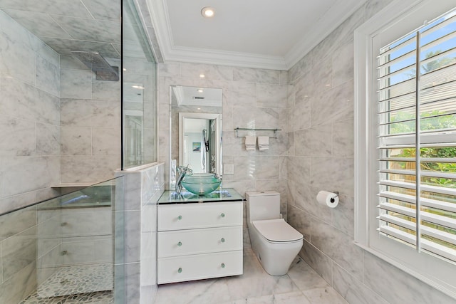 bathroom with a tile shower, vanity, crown molding, toilet, and tile walls