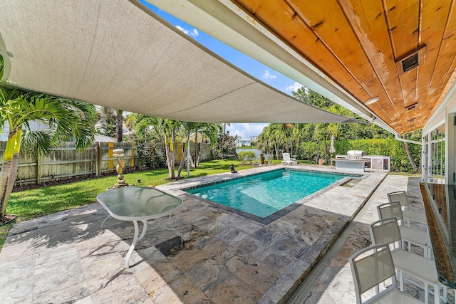 view of swimming pool with area for grilling, a yard, exterior kitchen, and a patio area