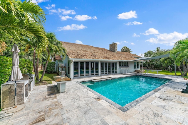 view of swimming pool featuring a patio area and exterior kitchen